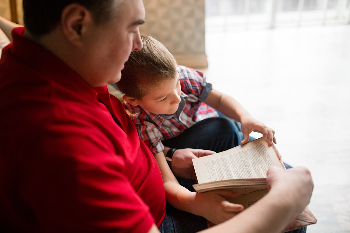 Man with young boy reading